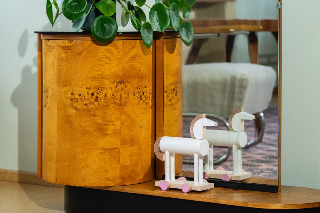 A wooden horse with pink wheels in front of a mirror in the Volman Villa